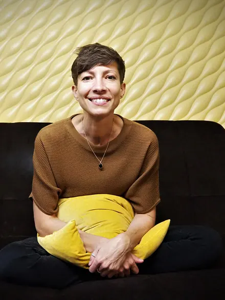 Christiane Yavuz sitzt lächelnd auf einem Sofa